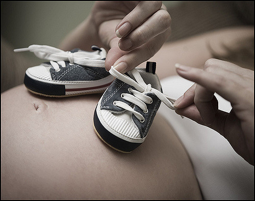 baby shoes over a preganant belly